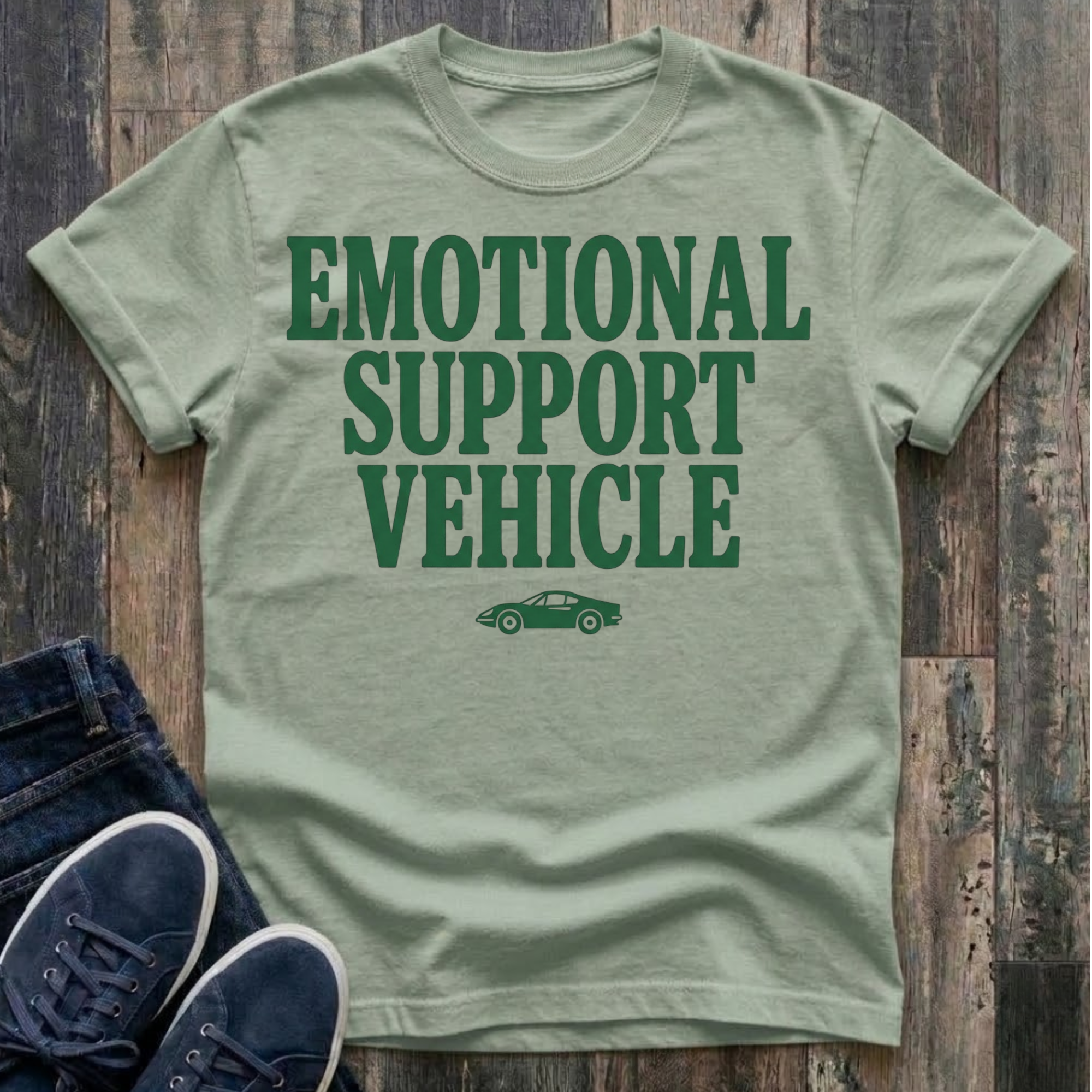 bay t-shirt with bold forest green block typography reading "Emotional Support Vehicle" with a small classic sports car silhouette centered beneath the text