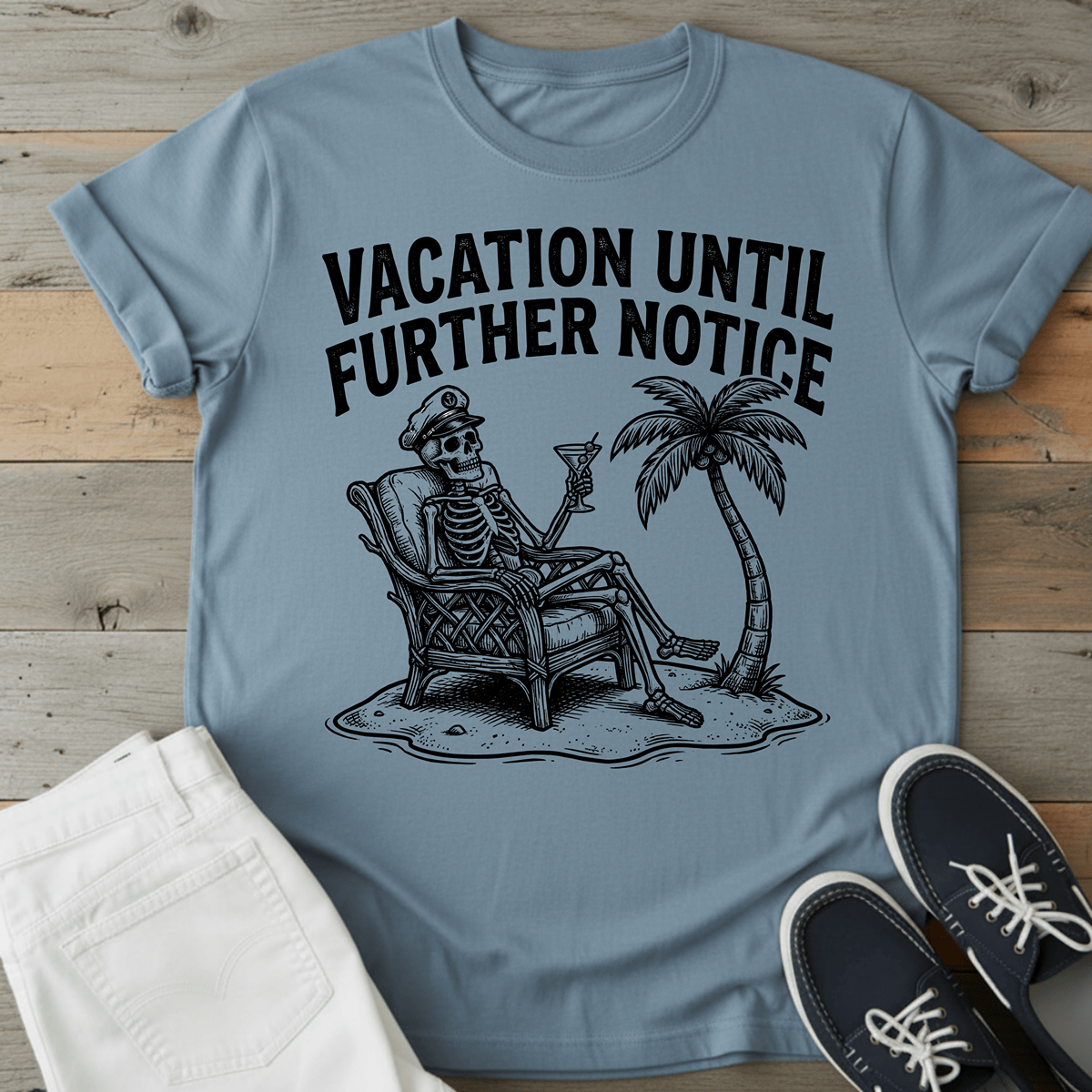 Retro Beach Skeleton T-Shirt featuring a skeleton relaxing with a drink under a palm tree, in light blue.